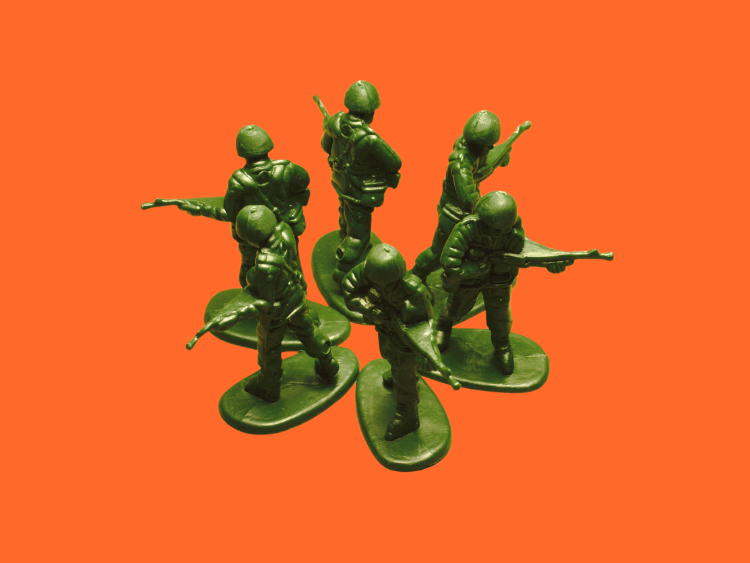 Five plastic toy soldiers stand in a circle facing outwards