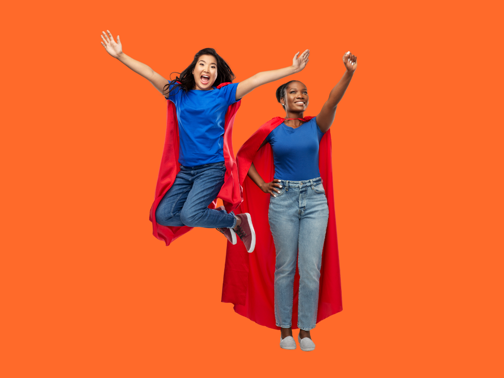 Two women wearing jeans, blue t-shirts and red capes